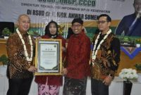 Foto : Didampingi Bupati Fauzi, dr Erliyati M.Kes menerima penghargaan dengan senyum kebanggaan 