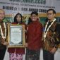 Foto : Didampingi Bupati Fauzi, dr Erliyati M.Kes menerima penghargaan dengan senyum kebanggaan 