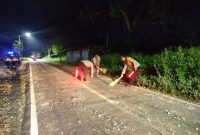 Foto: Dua anggota Polsek Manding bersama warga sigap membersihkan tumpahan batu cor yang berserakan di Jalan Raya Desa Jabaan, guna mencegah risiko kecelakaan. Dokumentasi RADAR9.ID/Redaksi.